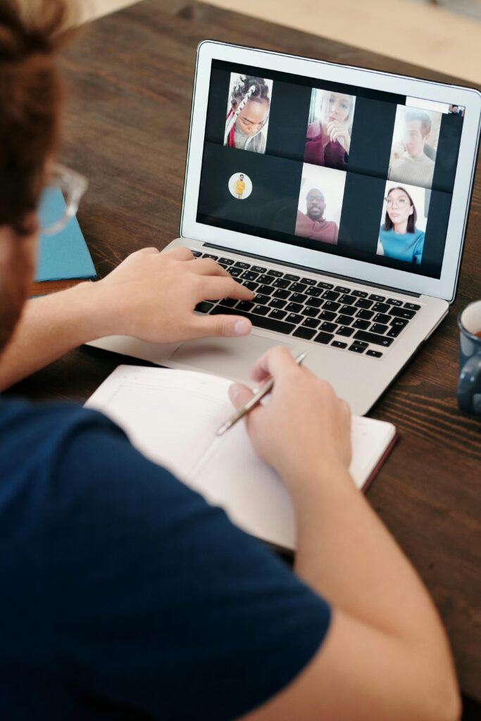pexels-photo-6147014-6147014 Person taking notes during a virtual meeting on a laptop screen with a diverse team.